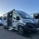 Camping-car gris stationné sur un parking, porte latérale ouverte