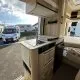 Intérieur d'un camping-car moderne avec cuisine équipée et espace de couchage.
