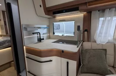 Cuisine moderne de camping-car avec évier, rangements et banquette.
