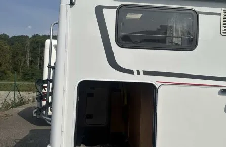 Vue arrière d'un camping-car avec soute ouverte, marque Dethleffs visible