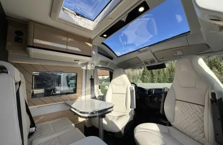 Intérieur d'un camping-car moderne avec sièges en cuir et toit panoramique.