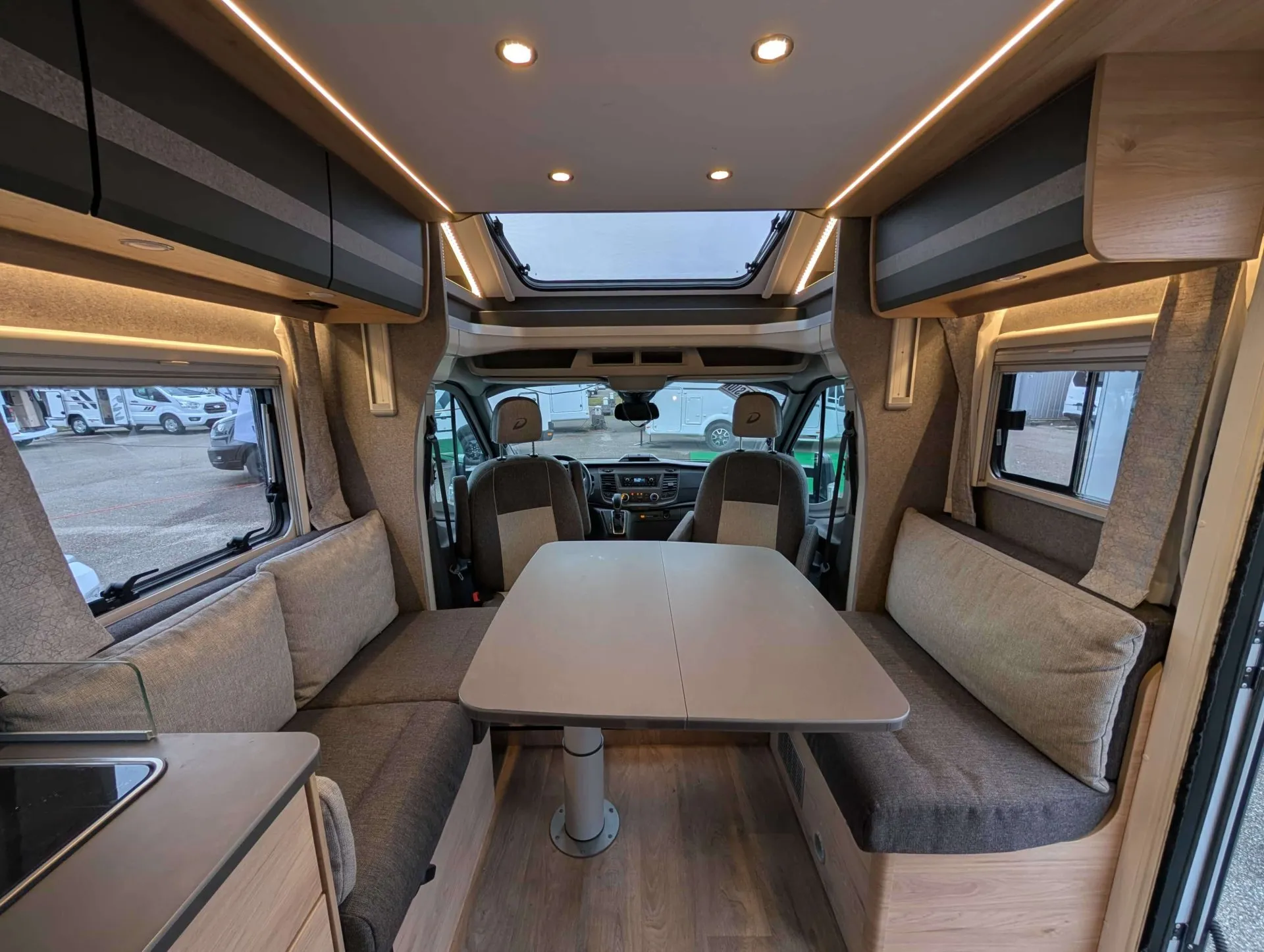 Intérieur d'un camping-car moderne avec table et banquettes grises
