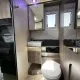 Salle de bain moderne dans un camping-car avec toilettes et lavabo intégrés.