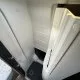 Douche compacte dans un camping-car moderne avec parois blanches et sol antidérapant.