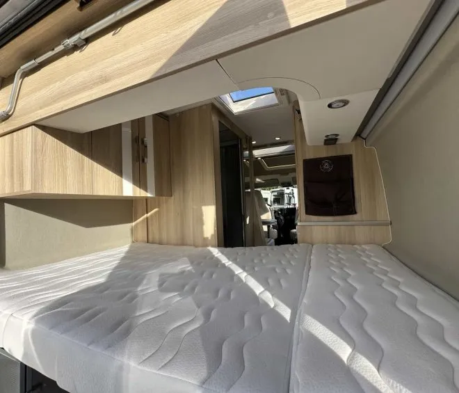 Intérieur d'un camping-car avec lit et rangements en bois clair
