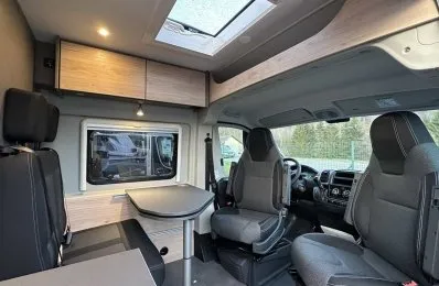 Intérieur d'un camping-car moderne avec sièges et table pliante.