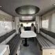 Intérieur spacieux d'un camping-car moderne avec banquettes et table centrale.