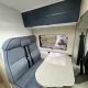 Intérieur d'un camping-car avec banquette et table pliante, vue sur fenêtre latérale.