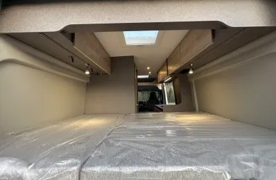 Intérieur d'un van aménagé avec lit double et rangements en bois clair