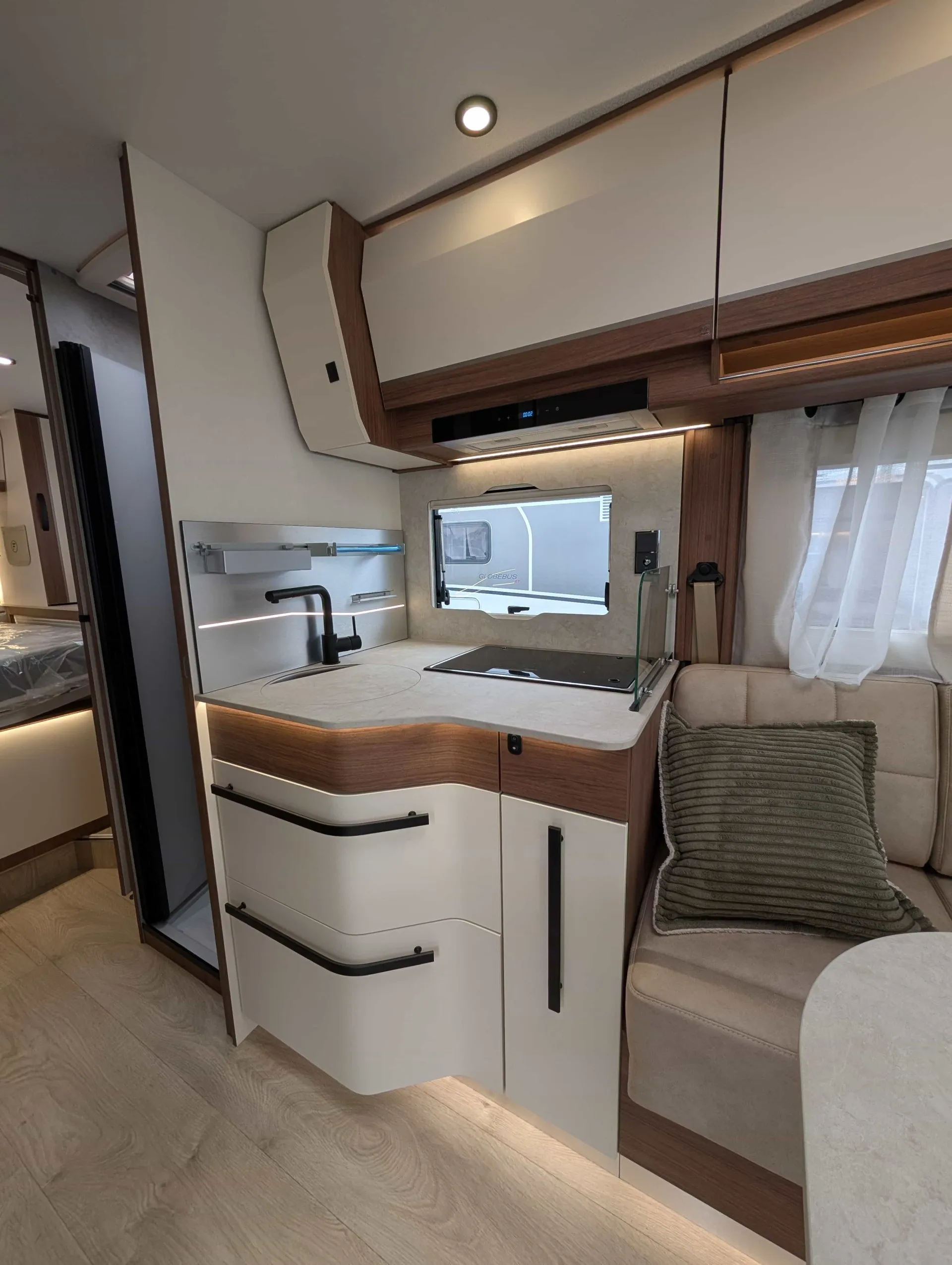 Cuisine moderne de camping-car avec évier, rangements et banquette.