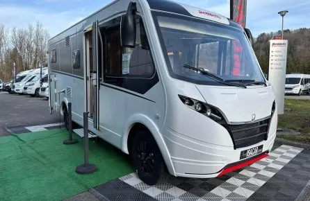 Camping-car Dethleffs blanc exposé sur un parking avec d'autres véhicules similaires.
