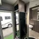 Intérieur d'une caravane moderne avec salle de bain et réfrigérateur visible.