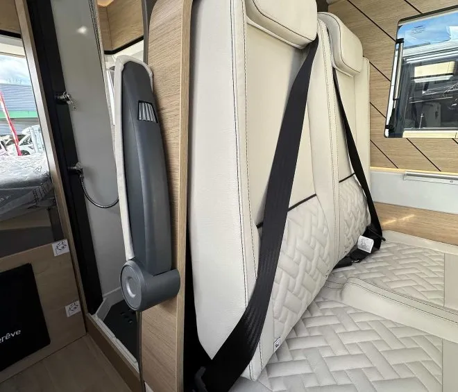 Siège de camping-car avec ceinture de sécurité et revêtement en cuir beige.