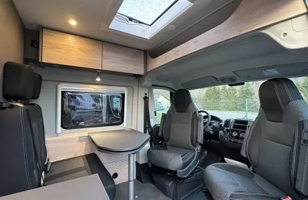 Intérieur d'un camping-car moderne avec sièges et table pliante.