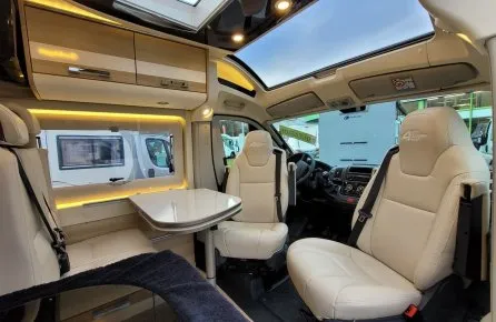 Intérieur d'un camping-car moderne avec sièges en cuir et table pliante.