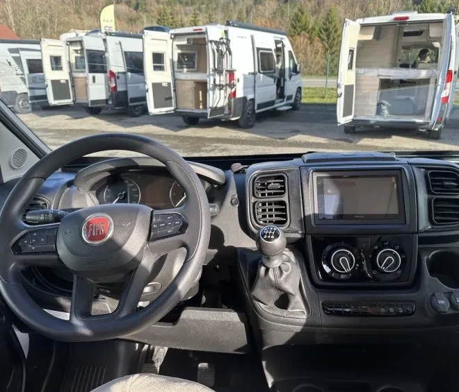 Intérieur d'un camping-car Fiat avec vue sur d'autres véhicules stationnés