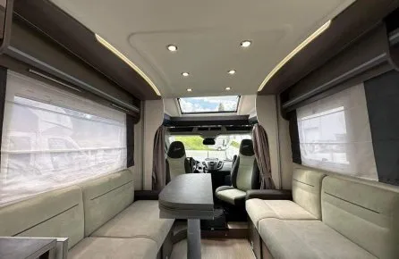 Intérieur spacieux d'un camping-car moderne avec sièges et table.