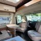 Intérieur d'un camping-car avec sièges et table, vue sur l'extérieur.