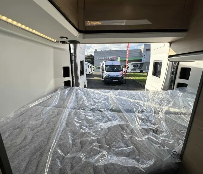Intérieur d'un camping-car avec lit, vue sur concessionnaire
