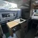 Intérieur d'un camping-car avec cuisine équipée et vue sur un autre véhicule stationné.
