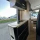 Intérieur moderne d'un camping-car avec cuisine équipée et rangements.