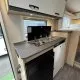 Cuisine compacte de camping-car avec évier, réfrigérateur et rangements.
