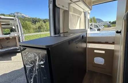 Intérieur d'un van aménagé avec vue sur l'extérieur et rangements intégrés