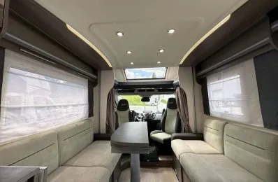 Intérieur spacieux d'un camping-car moderne avec sièges et table.