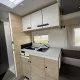Cuisine moderne de camping-car avec évier, plaques de cuisson et rangements en bois clair.
