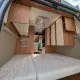 Intérieur d'un van aménagé avec lit et rangements en bois clair.