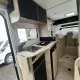 Intérieur moderne d'un camping-car avec cuisine équipée et rangements en bois clair.