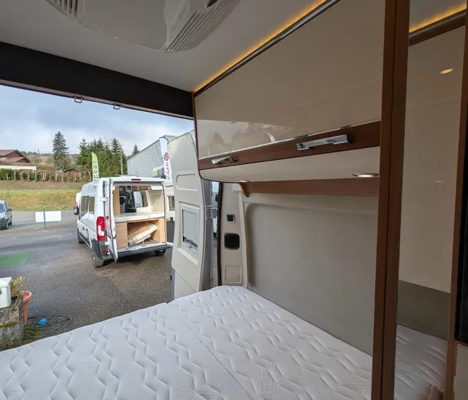 Intérieur d'un camping-car avec lit et rangements visibles