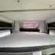 Intérieur d'un camping-car avec un lit double et un hublot ouvert