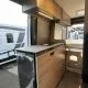 Intérieur d'un van aménagé avec cuisine moderne et rangements en bois clair.