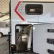 Compartiment de rangement ouvert d'une caravane sous abri, avec matelas emballé à l'intérieur.