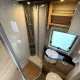 Salle de bain compacte dans un camping-car avec douche, lavabo et toilettes.