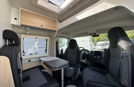 Intérieur d'un camping-car moderne avec sièges et table pliante.