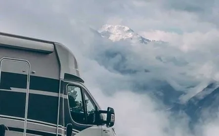 Camping-car stationné devant un paysage montagneux nuageux