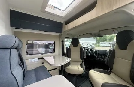 Intérieur d'un camping-car moderne avec sièges et table pliante.