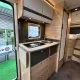 Cuisine moderne d'un camping-car avec évier, plaques de cuisson et rangements en bois clair.