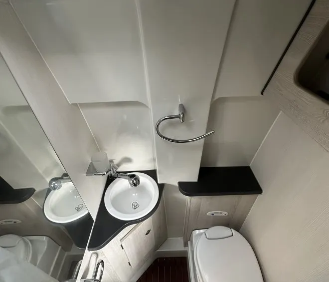 Salle de bain compacte avec lavabo, toilettes et douche dans un espace restreint.