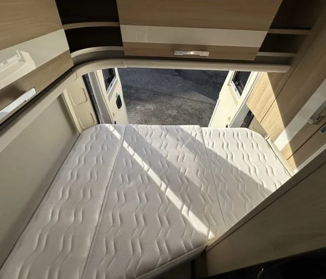 Intérieur d'un camping-car avec lit pliant et rangements en bois clair