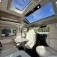 Intérieur d'un camping-car moderne avec sièges en cuir et toit panoramique.
