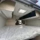 Intérieur d'un van aménagé avec lit et rangements en bois clair.