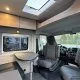 Intérieur d'un camping-car moderne avec sièges et table pliante.