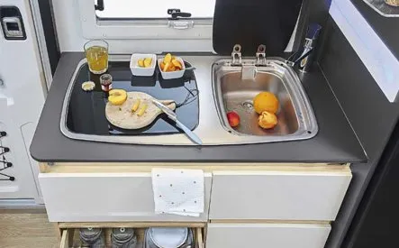 Cuisine compacte de camping-car avec évier, planche à découper et fruits