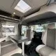 Intérieur d'un camping-car moderne avec sièges et table, vue sur l'extérieur.