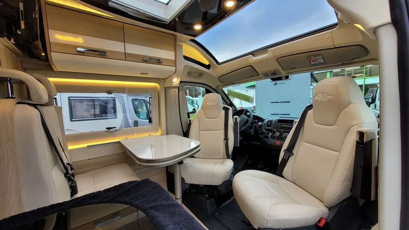 Intérieur d'un camping-car moderne avec sièges en cuir et table pliante.