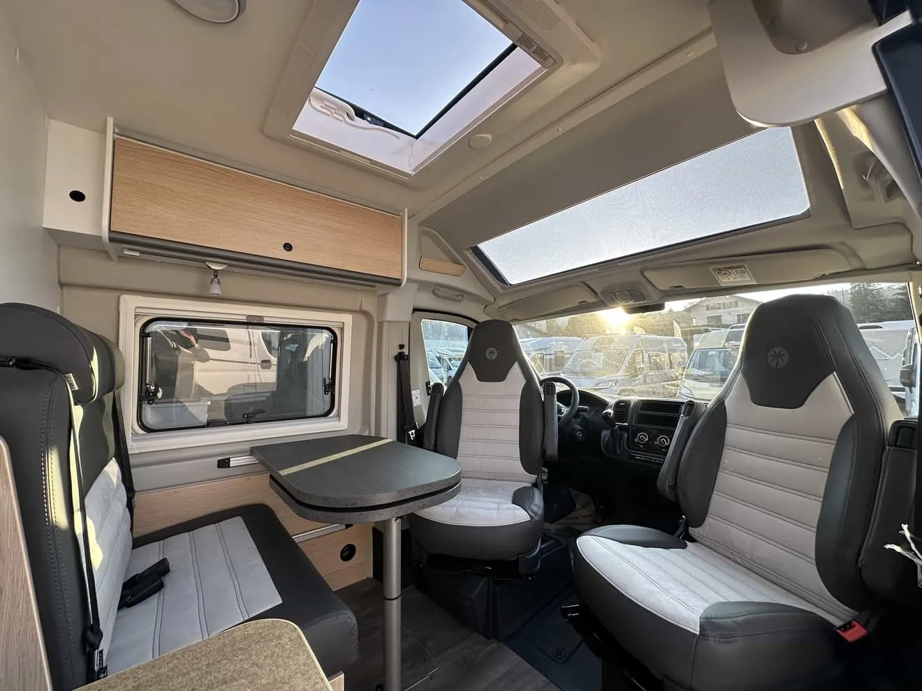 Intérieur d'un camping-car moderne avec sièges et table, éclairage naturel.