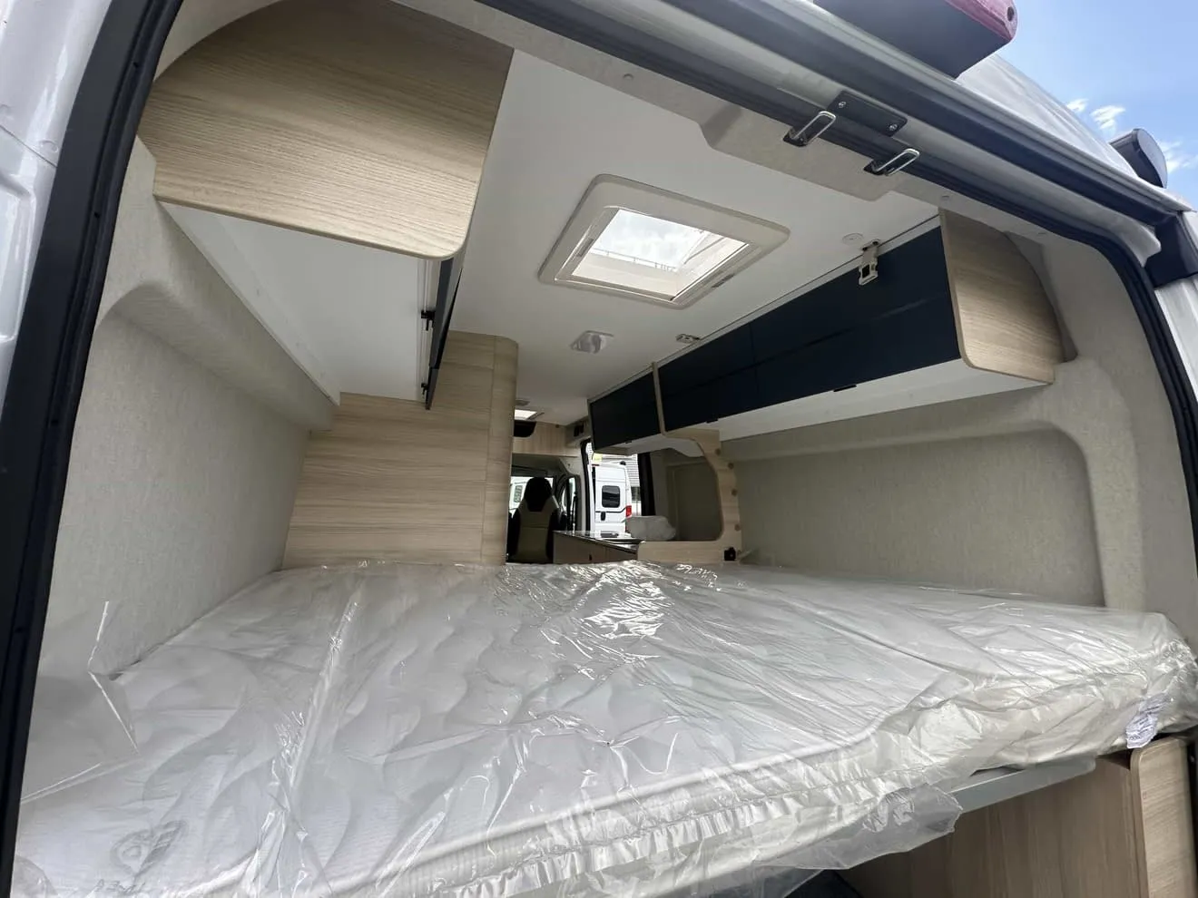 Intérieur d'un van aménagé avec lit et rangements en bois clair.